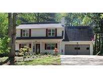 Charming two-story home featuring red shutters, a well-manicured lawn, and an attached two-car garage at 4314 Saddlecreek Ct, Auburn, GA 30011