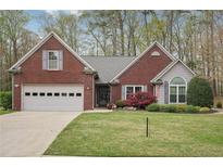 Charming brick home featuring an attached garage, manicured lawn, and a beautifully landscaped front yard at 1145 Prospect Mill Dr, Lawrenceville, GA 30043