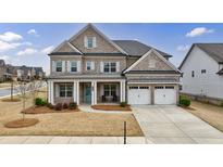 Charming two-story brick home featuring a welcoming front porch, two-car garage, and beautifully landscaped front yard at 4405 Croftshire Pl, Cumming, GA 30040