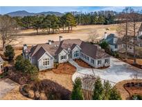 Stunning home exterior featuring stone accents, a well-manicured lawn, and a circular driveway leading to a golf course view at 1304 Marietta Country Club Nw Dr, Kennesaw, GA 30152