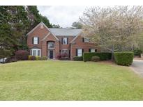 Charming two-story brick home with a well-manicured lawn and blooming tree at 2555 Stonevalley Ln, Cumming, GA 30041