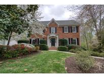 Charming red brick two-story home featuring a beautifully landscaped front yard with mature trees and flowering shrubs at 1510 Wood Thrush Way, Marietta, GA 30062