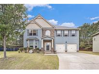 Charming two-story home with a well-manicured lawn, attached two car garage, and classic blue siding at 415 Damascus Ct, Fairburn, GA 30213
