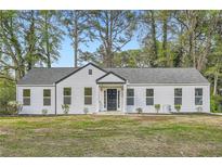 Newly renovated single story house with white siding, black trim, and a landscaped front yard with mature trees at , Atlanta, GA 30311