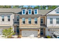 Charming brick townhome featuring a two-car garage and a covered front porch entry at 5010 Towneship Creek Rd, Roswell, GA 30075