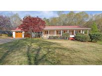 Charming home with a red metal roof, a covered front porch, and a well-manicured lawn at 6690 Pine Ridge Cir, Cumming, GA 30041