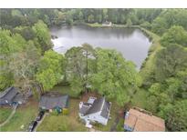 Scenic aerial view of home near a lake surrounded by lush green trees, offering a tranquil setting at 1077 Mainstreet Valley Dr, Stone Mountain, GA 30088