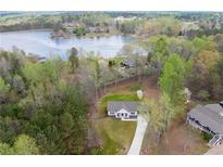 Aerial view of a charming home with a large front yard, surrounded by trees and overlooking a serene lake at 121 Tricias Way, Temple, GA 30179