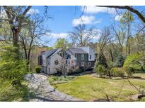 Charming two-story home with an attractive front yard and lovely landscaping on a partly cloudy day at 10845 Shallowford Rd, Roswell, GA 30075