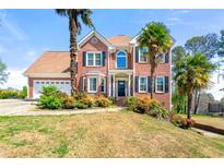 Beautiful two-story brick home with palm trees and a manicured lawn on a sunny day at 2245 Friars Gate Dr, Lawrenceville, GA 30043