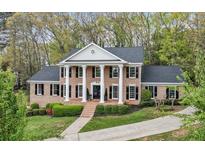 Stately brick home with white columns, black shutters, and mature landscaping provides classic curb appeal at 6124 Kings Mountain Ct, Stone Mountain, GA 30087