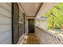 Charming front porch with wooden flooring, black door, and wooden lattice fencing at 104 Natchez Trce, Atlanta, GA 30350