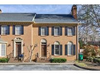 Charming townhome featuring a brick facade, black shutters, and well-maintained landscaping with a blue sky backdrop at 272 Windsor Pkwy, Atlanta, GA 30342