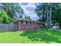 Charming brick home featuring a spacious lawn and mature trees creating a serene and private setting at 3932 Lindsey Dr, Decatur, GA 30035