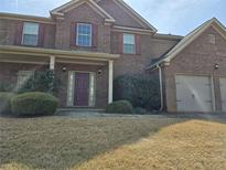 Charming two-story brick home featuring a two-car garage, covered entrance, and well-manicured landscaping at 1440 Gallup Dr, Stockbridge, GA 30281