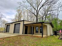 A cozy one-story home showcasing a covered porch and two garage doors, all in a natural setting at 300 Outlaw Rdg, Canton, GA 30115