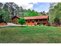 Charming log home with a well-manicured lawn and a welcoming front porch at 1791 Walker Sw Rd, Conyers, GA 30094