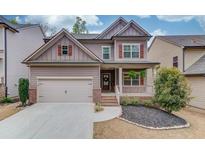 Charming two-story home featuring a covered front porch, two-car garage, and manicured landscaping at 5036 Maplecliff Dr, Sugar Hill, GA 30518