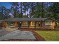 Charming brick home with a covered carport, landscaped front yard, and inviting front porch at 2695 Peeler Rd, Dunwoody, GA 30360