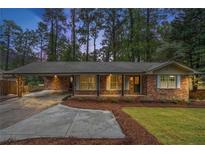 Charming brick home with a covered carport, front porch, and manicured lawn at 2695 Peeler Rd, Dunwoody, GA 30360