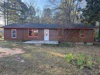 Charming single-story home featuring brown wood siding, a white front door, and orange window trim at 144 Flat Rock Rd, Oxford, GA 30054