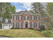 Elegant two-story brick home with symmetrical facade, black shutters, and a well-manicured front lawn at 4503 Payton Oaks Ne Pl, Atlanta, GA 30345