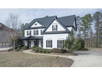 Beautiful two-story home featuring manicured landscaping, a curved walkway, and classic black and white design elements at 6025 Golf View Xing, Locust Grove, GA 30248