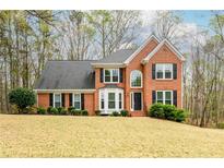 Charming two-story brick home with a well-manicured lawn and mature trees at 1885 Oak Wind Ln, Buford, GA 30519