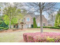 Charming two-story brick home featuring a manicured lawn with mature trees and blooming bushes at 2281 Bransley Pl, Duluth, GA 30097