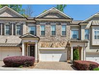 Brick townhome featuring an attached two-car garage and a well-manicured lawn at 828 Canterbury Overlook Ne, Atlanta, GA 30324