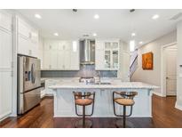 Modern kitchen features stainless steel appliances, granite counters, tile backsplash, and seating at the kitchen island at 828 Canterbury Overlook Ne, Atlanta, GA 30324
