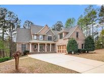 Elegant brick home featuring a manicured lawn, complemented by a spacious driveway and attached two car garage at 7497 Treehouse Ct, Douglasville, GA 30135