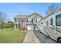 Charming two-story home featuring grey siding, white trim, front yard, RV parking, and well-manicured lawn at 1218 Cabots Ln, Auburn, GA 30011