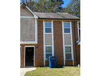 A brick townhouse with a dark front door and two sets of windows, complemented by a well-maintained lawn at 6527 River Park Dr, Riverdale, GA 30274