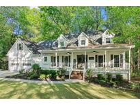 Charming home exterior featuring a welcoming front porch, well-manicured lawn and beautiful, mature trees at 2100 Kings Valley Dr, Lawrenceville, GA 30043