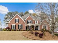 Charming two-story brick home featuring black shutters, mature trees, and a well-manicured lawn, perfect for suburban living at 214 Cedar Woods Way, Canton, GA 30114
