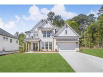 Beautiful two-story home features a manicured lawn, two-car garage, and a classic white brick facade at 7043 Foundry Dr, Woodstock, GA 30188
