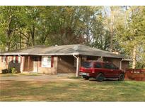 Quaint brick home with a mature lawn, featuring a driveway and a red SUV parked in front at 1185 Highway 162, Covington, GA 30016