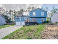 Charming blue two-story home with a driveway and a welcoming front deck, surrounded by lush greenery at 4809 Burlington Nw Ct, Acworth, GA 30102