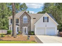 Charming two-story home featuring a stone facade, white siding, a two-car garage, and a well-maintained front yard at 277 Edison Dr, Stockbridge, GA 30281