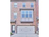 Charming brick townhome featuring an attached garage and inviting front entrance at 1147 Laurel Valley Ct, Buford, GA 30519