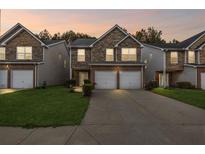 Charming townhome exterior featuring stone accents and a two-car garage, set against a twilight sky at 8849 Seneca Rd, Palmetto, GA 30268