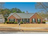 Charming brick home featuring green shutters, a well-maintained lawn, and a welcoming entrance at 5780 Village Loop, Fairburn, GA 30213
