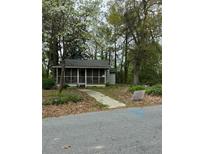 Small home with a screened-in porch nestled amongst mature trees and a walkway to the entrance at 556 Kay St, Forest Park, GA 30297