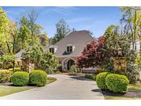 Stately home featuring beautiful landscaping, a circular driveway, and stone pillar light fixtures at 5780 Heards Forest Dr, Atlanta, GA 30328