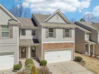 Charming townhome with stone accents, a two-car garage, and well-maintained landscaping at 5890 Vinyard Ln, Cumming, GA 30041