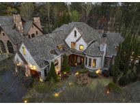 Stunning exterior elevation of stone home with turret, manicured landscaping and mature trees at 290 Ardsley Ln, Alpharetta, GA 30005