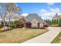 Charming brick home features manicured lawn, mature trees, and a paved driveway leading to the entrance at 6730 Waterbury Way, Cumming, GA 30040
