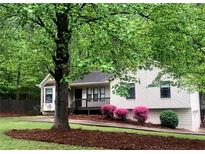 Charming single Gathering home with a welcoming front porch, lush green lawn, and mature trees at 647 Sunshine Nw Trce, Acworth, GA 30102