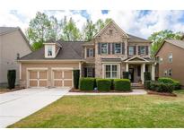 Charming two-story brick home with a well-manicured front yard and an attached two-car garage at 4421 Wooded Oaks Nw, Kennesaw, GA 30152